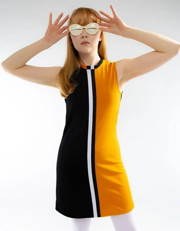 Woman wearing a black and yellow dress with white stripes on a plain background
