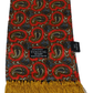 A Tootal silk scarf with a red, black, and gold paisley pattern and a gold fringe, shown with its black cardboard header card.