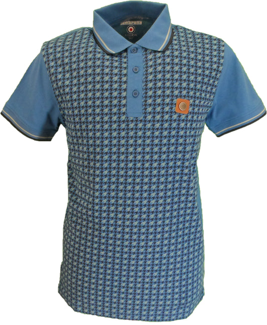 A men's short-sleeve polo shirt featuring a blue and white houndstooth pattern across the body, solid light blue sleeves, and a matching light blue collar. It has a three-button placket and a small circular orange patch on the left chest.