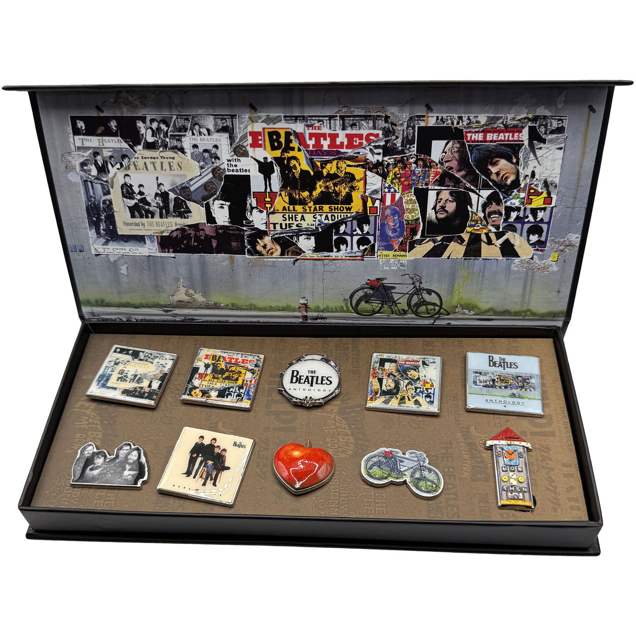 A Beatles-themed gift box set displayed open, featuring a large collage of The Beatles album art on the inside lid and multiple small album-themed pins and badges arranged on a brown textured base inside the box.