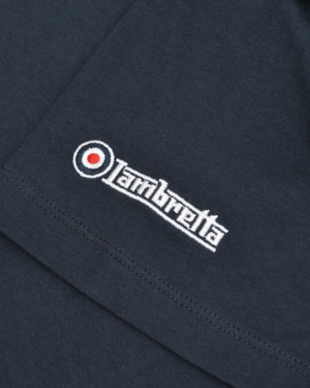 Close-up of a dark navy blue fabric garment featuring a white embroidered 'Lambretta' logo with a red target accent.
