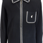 A black long-sleeve knit polo shirt by Gabico, featuring white braided trim along the collar, front placket, pocket, and hem, with a white embroidered logo on the chest pocket.
