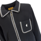 A close-up of a black long-sleeve collared shirt by GariccI, featuring a pointed collar and chest pocket trimmed with a white and black geometric pattern, and a small white logo on the pocket.