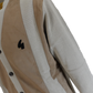 A close-up of a beige and off-white color-blocked cardigan sweater with a black embroidered logo on the chest, set against a plain white background.