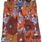 A folded long-sleeve button-up shirt by Mazeys, featuring a bold 1970s-style floral print in orange, rust brown, mustard yellow, and mauve on a white background.