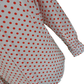 A close-up of a white long-sleeve blouse or dress with a red polka dot pattern, showing the fabric texture and a cuff on a plain white background.